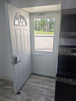 Una habitación con una puerta blanca, un ventanal y un horno empotrado.