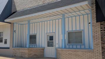 A building with a brick facade, a covered entrance with blue trim, and a door with a window.