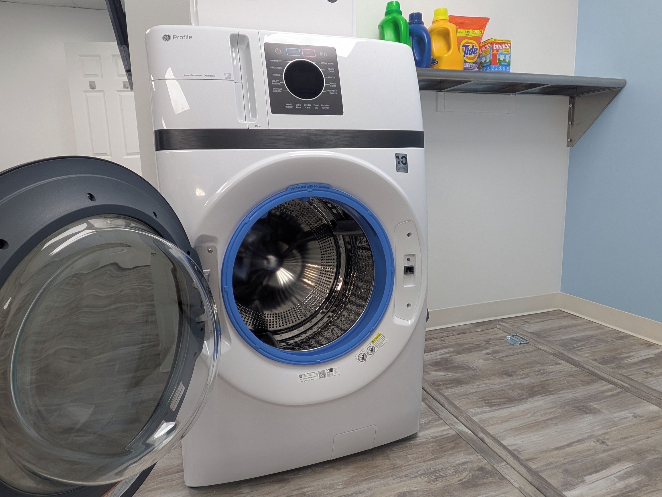 A front-loading washing machine with a blue door, a control panel, and a detergent dispenser.