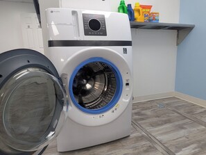 Una lavadora de carga frontal con puerta azul, un panel de control y un dispensador de detergente.
