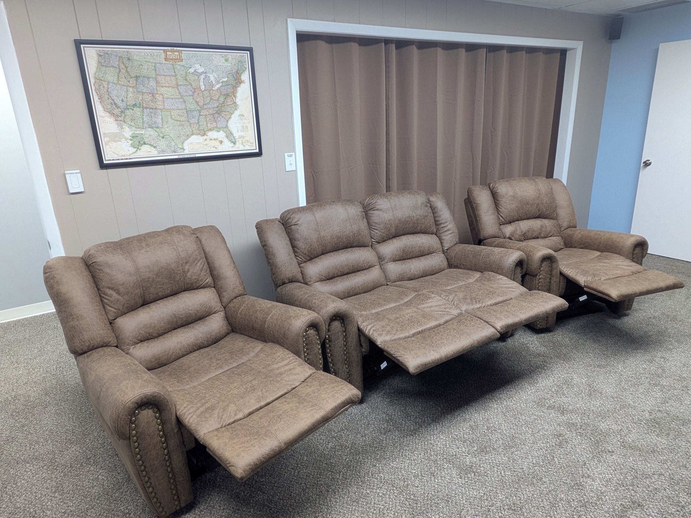 A room with three reclining chairs and a large map on the wall.