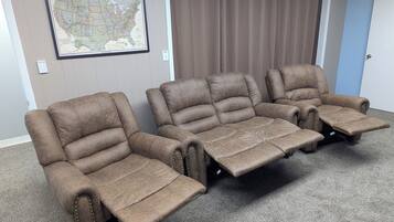 A room with three reclining chairs and a large map on the wall.