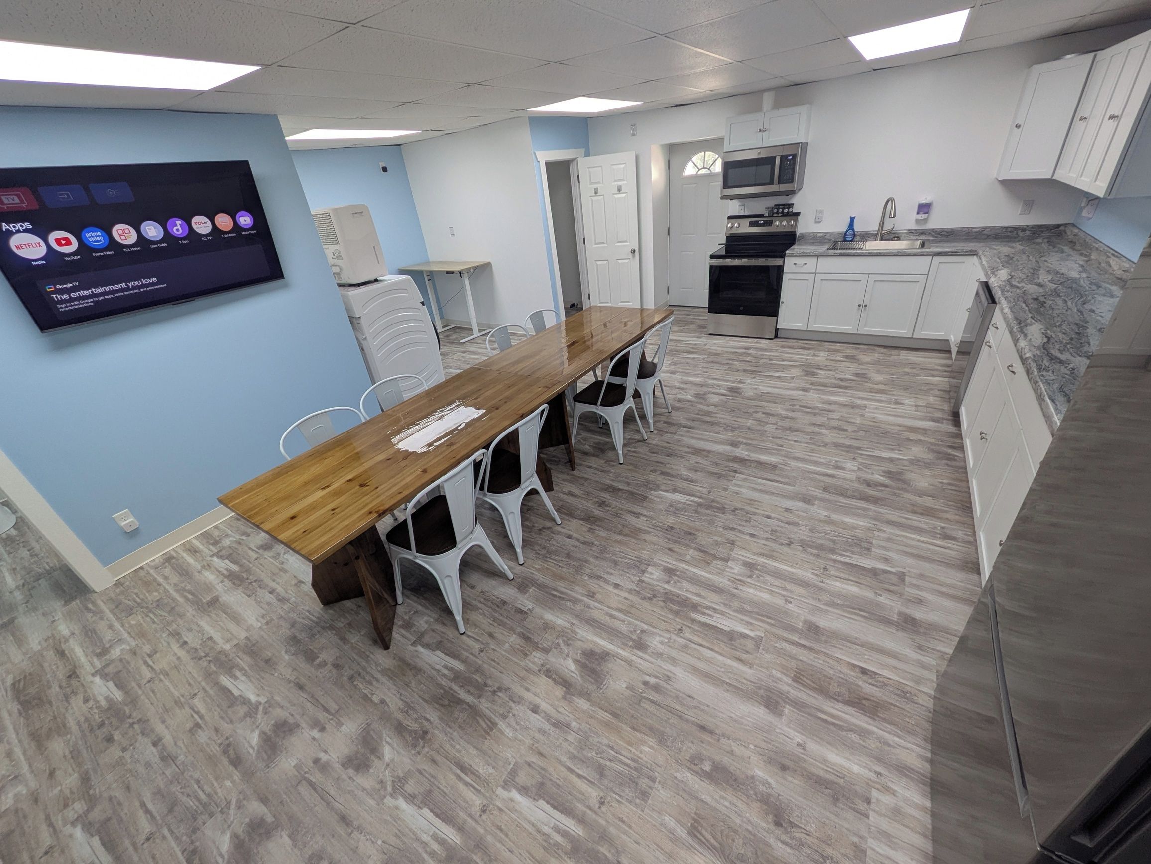 A modern kitchen with a wooden table and white chairs, a built-in oven, and a microwave.