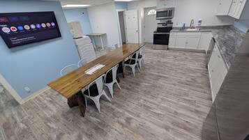 A modern kitchen with a wooden table and white chairs, a built-in oven, and a microwave.