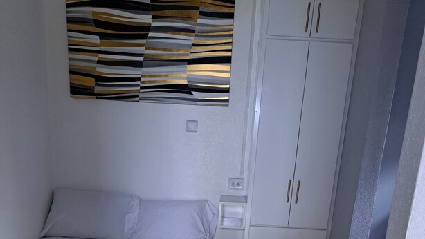 Un dormitorio con cama, armario y una obra de arte colgada en la pared.