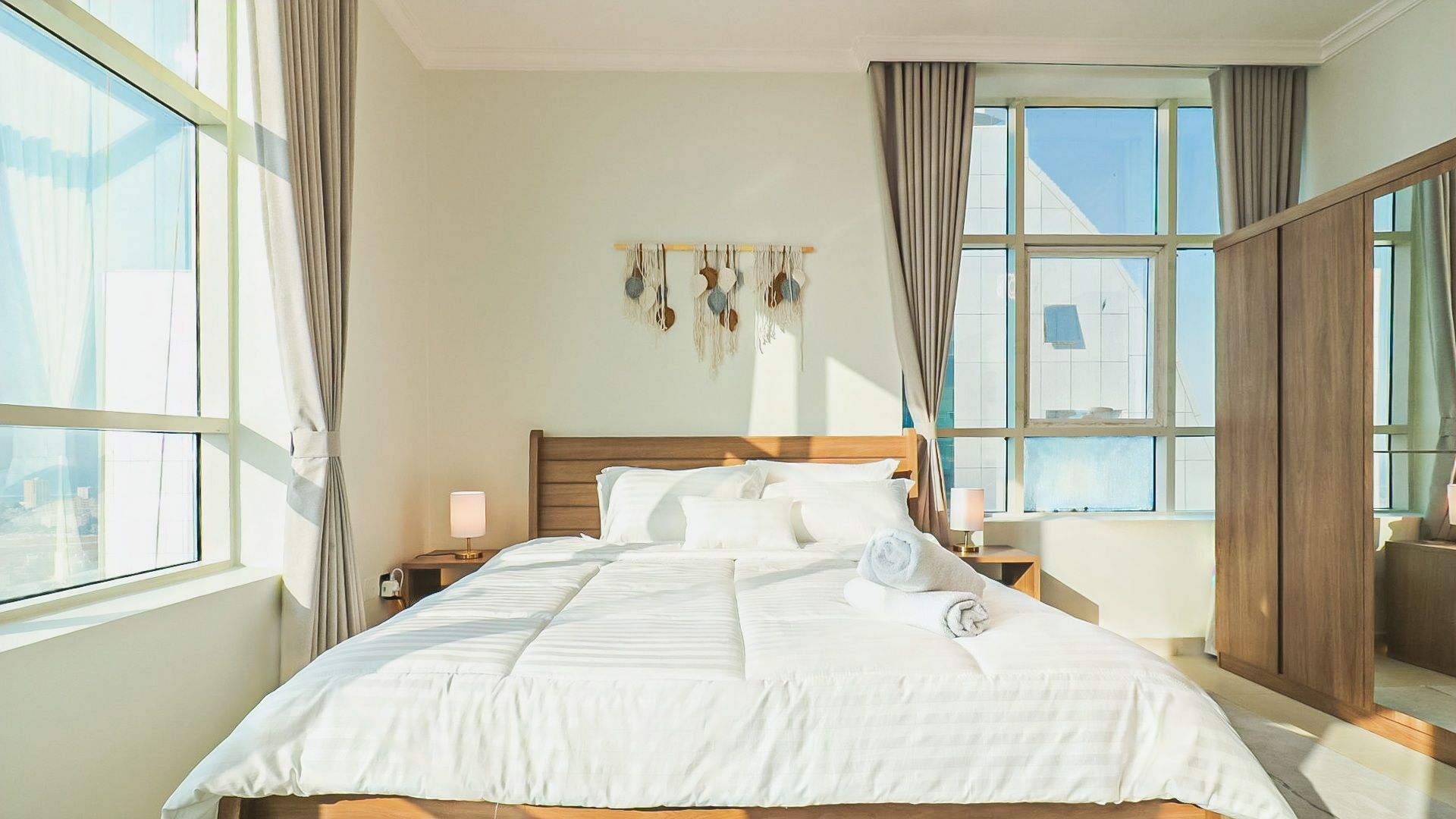 Camera d'albergo con un letto grande, due comodini, un elemento decorativo a parete e vista dalla finestra.