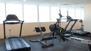 Ein Fitnessraum mit Laufbändern, Fahrrädern und Rudergeräten.