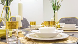 Ein Tisch ist mit weißem Geschirr, goldenen Akzenten und dekorativen Vasen gedeckt.