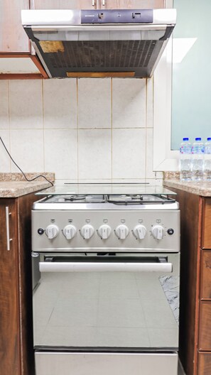 A kitchen with a stove, oven, and tiled backsplash. - City/Sea Scenery At Prestige 1BR  With Pool & Gym (Ajman)