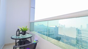 Een balkon met een glazen hekwerk, een klein rond tafeltje met een potplant en een stoel.