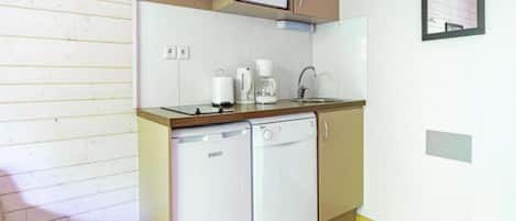 Una kitchenette compacta equipada con microondas, cafetera y lavavajillas.