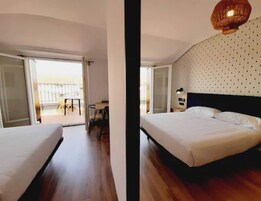 A hotel room with a bed, a desk, and a balcony.