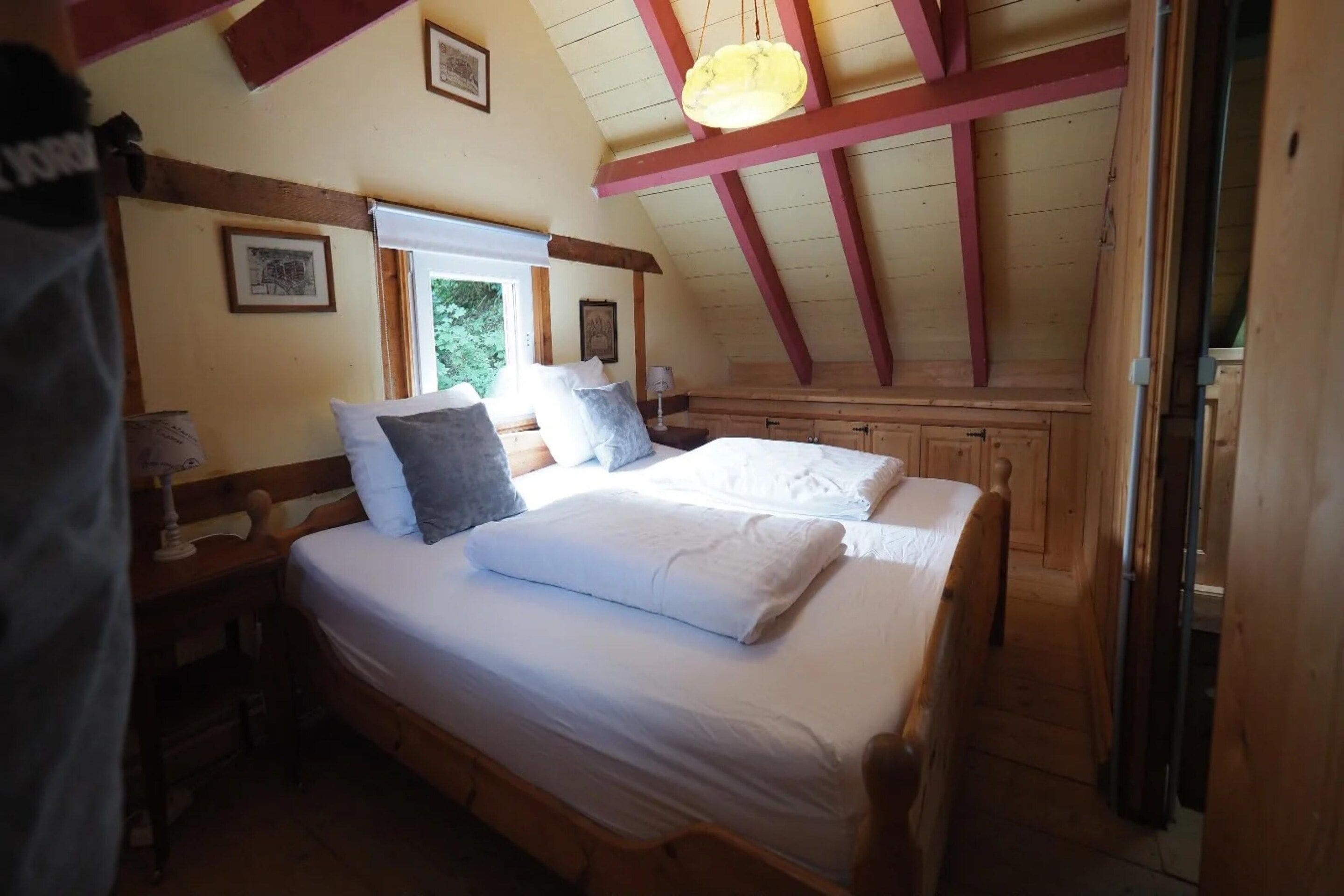 Une chambre avec deux lits, des poutres en bois et des tableaux encadrés aux murs.