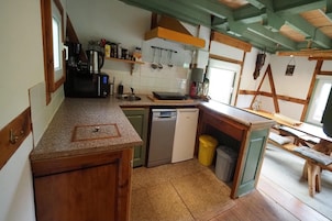 Cocina compacta con lavavajillas, pileta y muebles de madera.
