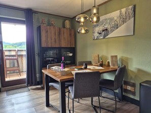 A dining area with a wooden table, chairs, and a view of the outdoors. - Mountain View Apartment Near Winterberg (Winterberg)