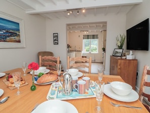 A dining area with a table set for breakfast, including croissants, a coffee pot, and striped mugs. - Iveridge (Whitby)