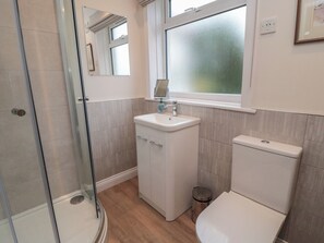 A bathroom with a glass shower enclosure, a sink with a mirror, and a toilet. - Iveridge (Whitby)