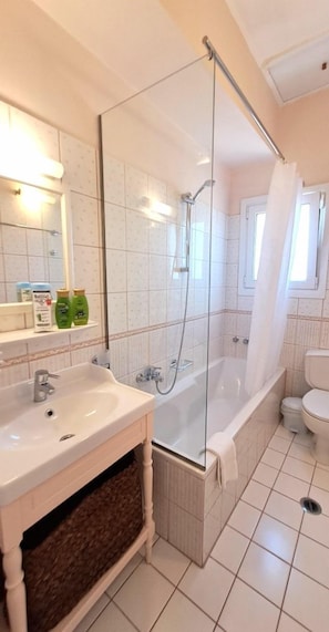 Een badkamer met een douchecabine van glas, een wit wastafelmeubel en een toilet.