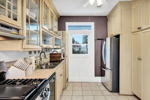 Une cuisine équipée d’une cuisinière à gaz, d’appareils électroménagers en acier inoxydable et de meubles de couleur claire.