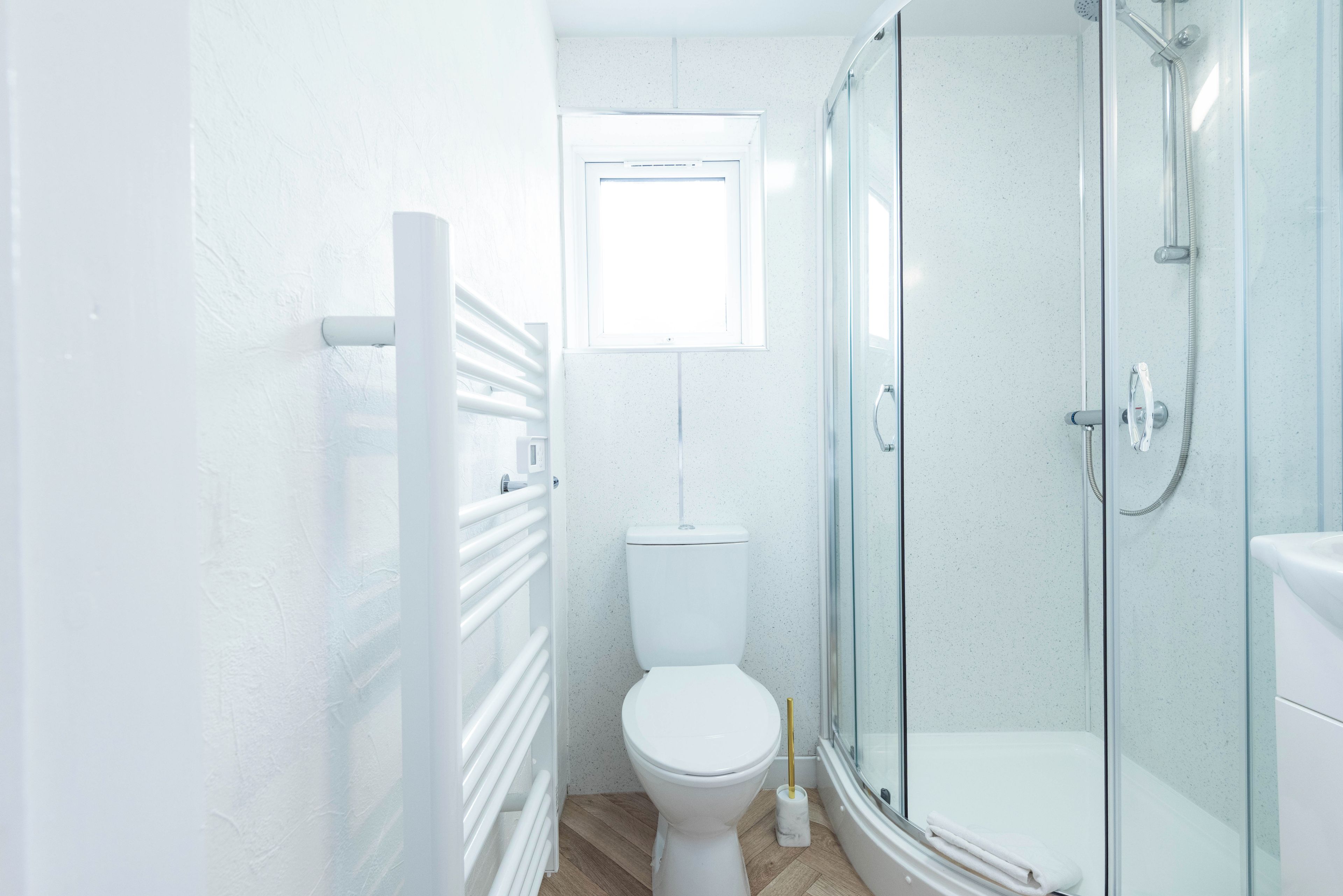 A bathroom with a toilet, a glass-enclosed shower, and a white radiator.