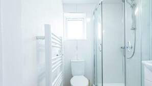 Ein Badezimmer mit Toilette, einer Duschkabine und einem weißen Handtuchwärmer.