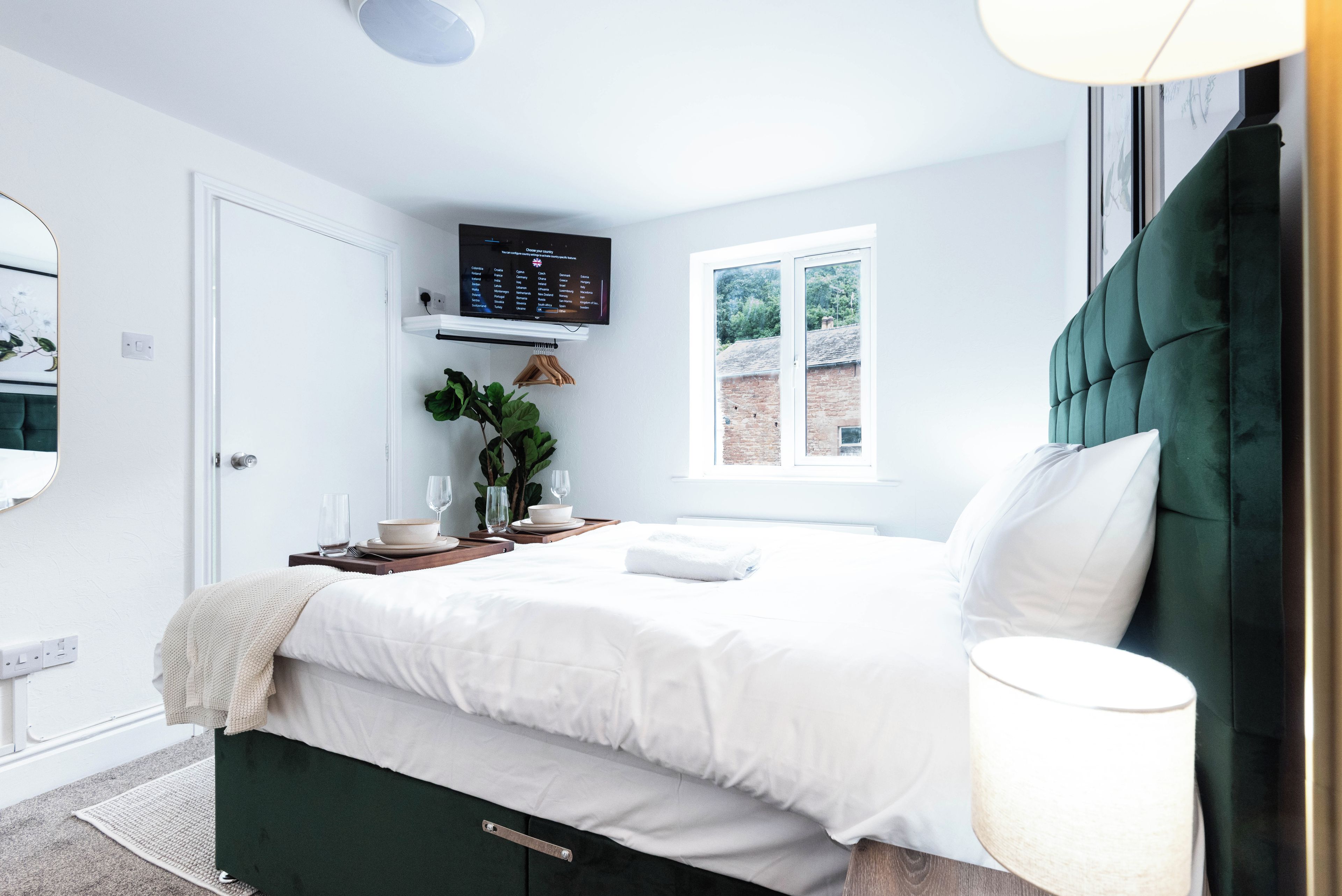 A modern bedroom with a bed, bedside table, and a TV mounted on the wall.