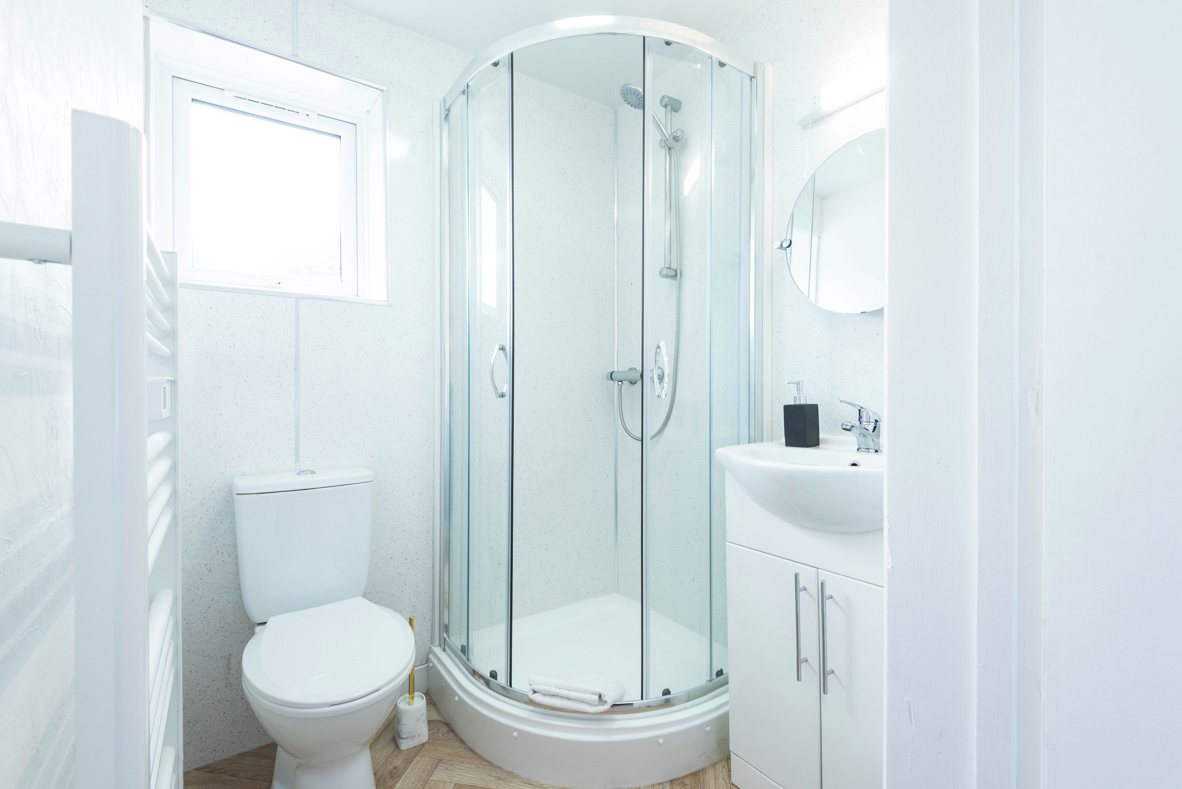 A modern bathroom with a glass-enclosed shower, a toilet, and a sink.