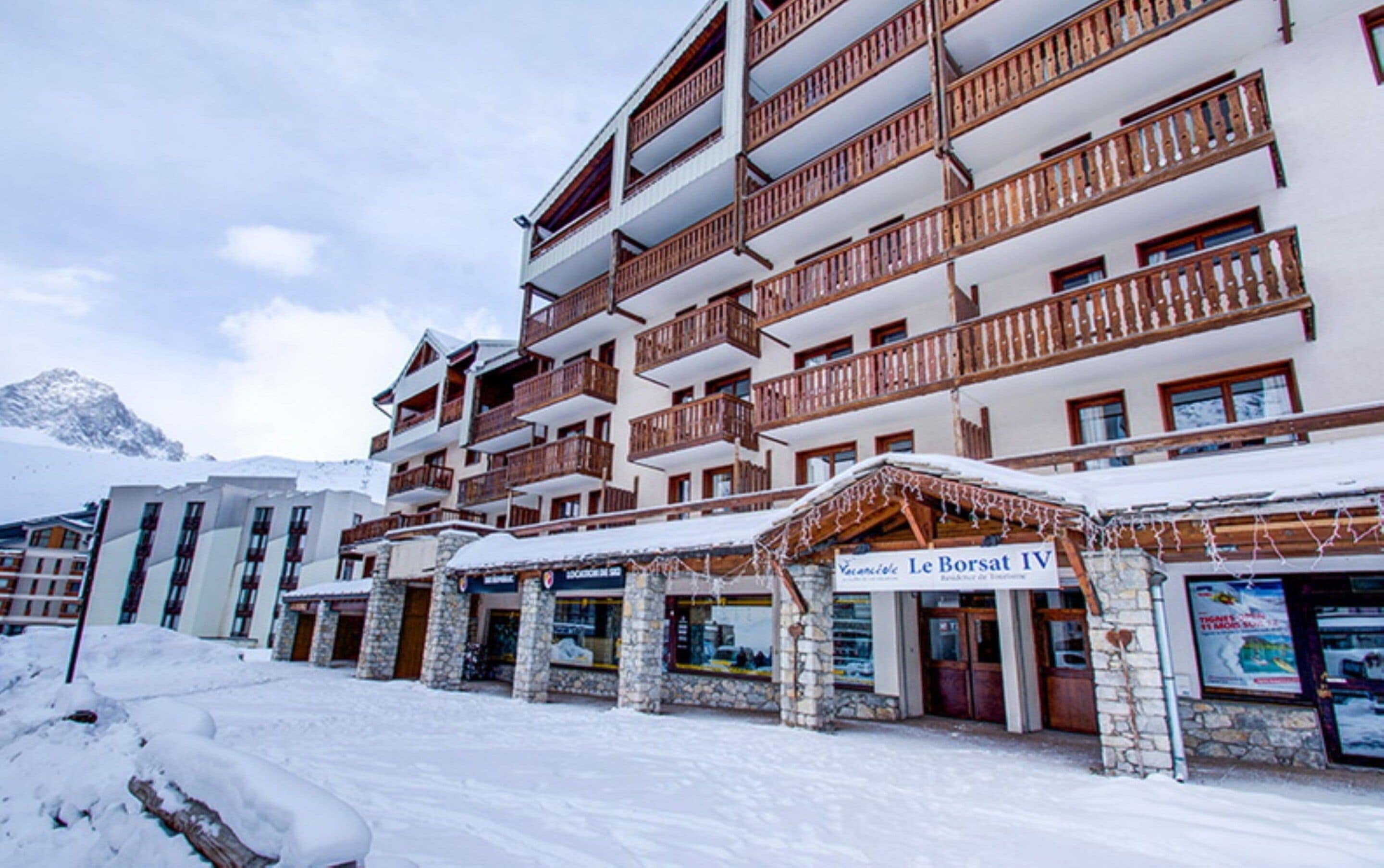 Un hôtel à plusieurs étages, doté de balcons, de piliers en pierre et d’une enseigne indiquant « Le Borsat IV ».