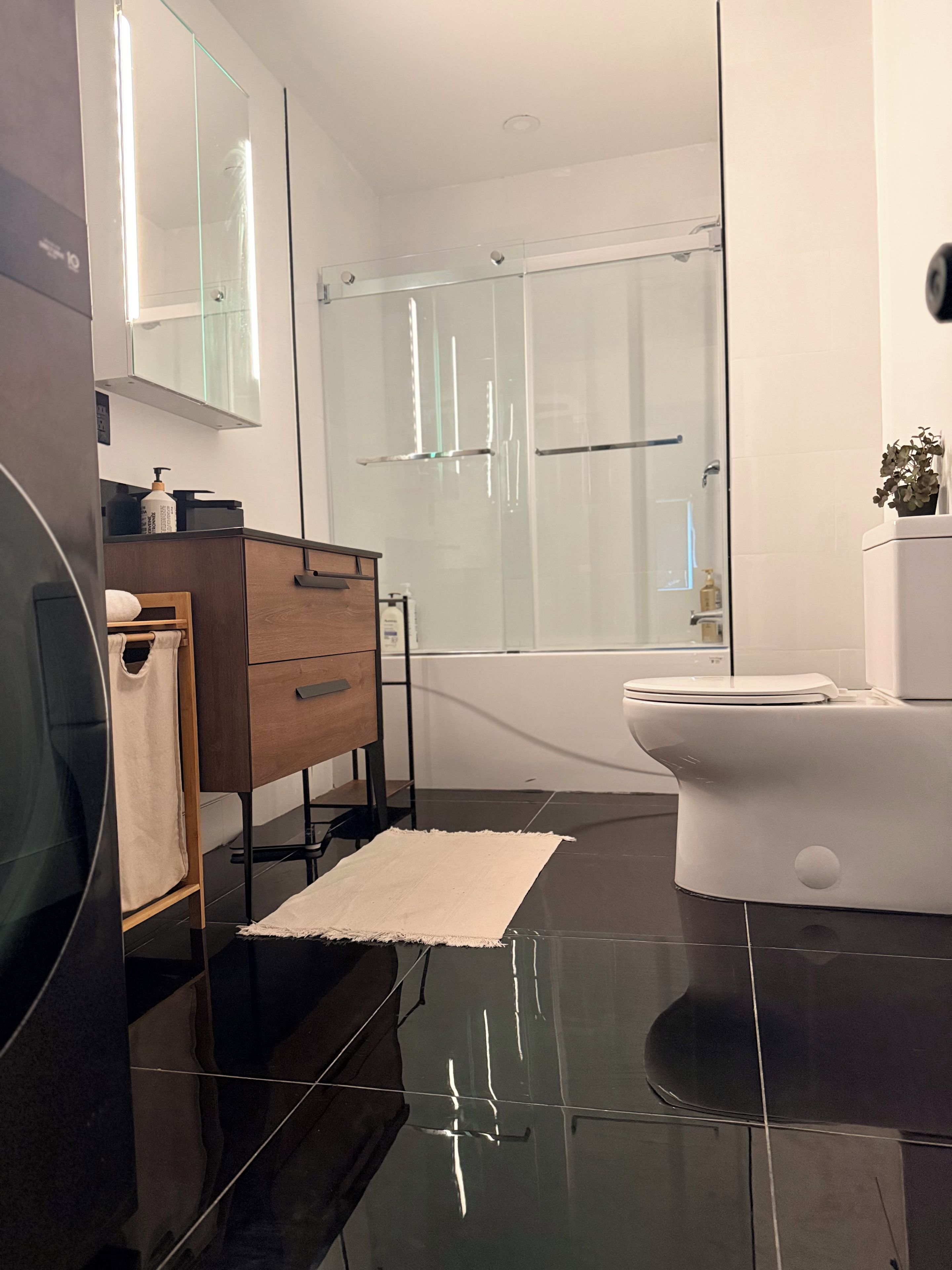 A modern bathroom with a glass shower enclosure, a wooden vanity, and a white toilet.