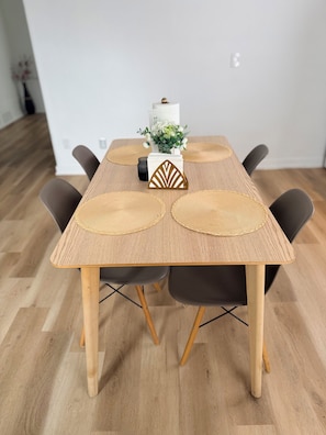 A dining table with a woven placemat, a decorative centerpiece, and black chairs.