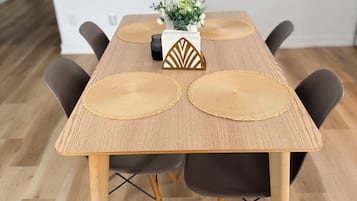 Et spisebord med en vævet bordskåner, en dekorativ geometrisk genstand og en vase med blomster.