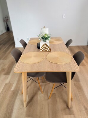 A dining table with a woven placemat, a decorative geometric object, and a vase with flowers.