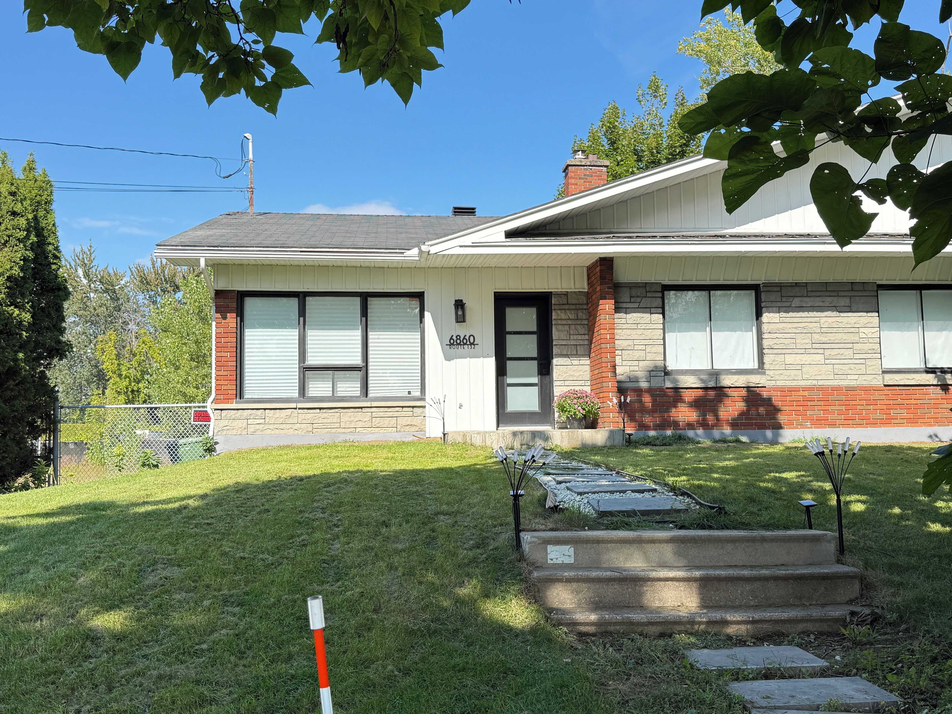 A residential house with a front yard, a mailbox, and a number '6860' on the door.