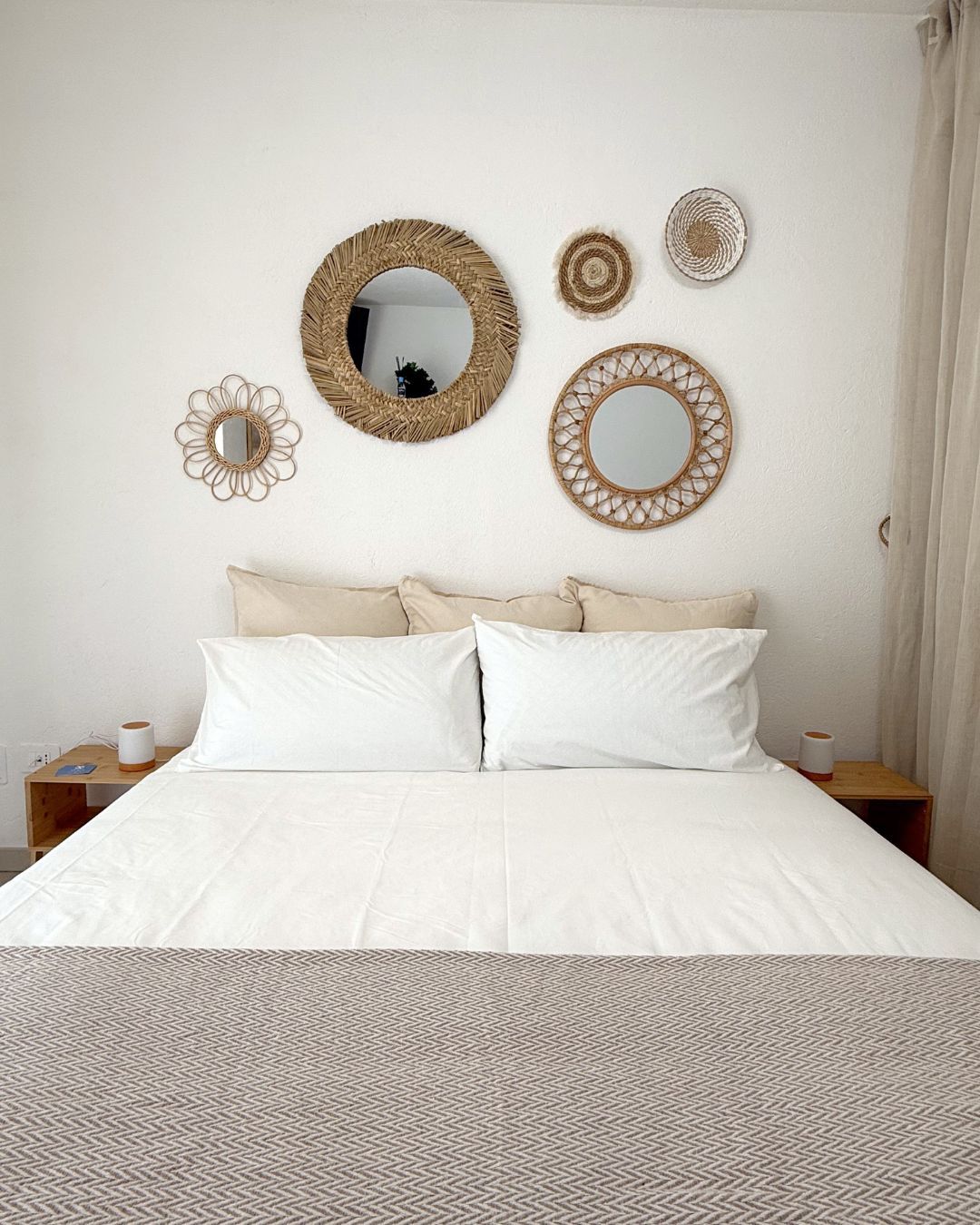 Une chambre à coucher comprenant un lit, deux tables de chevet et trois miroirs fixés au mur.