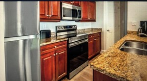 A kitchen with stainless steel appliances, wooden cabinets, granite countertops, and a built-in oven. - Family friendly, Orlando fully equipped 2-bedroom condo over Christmas break. (Orlando)
