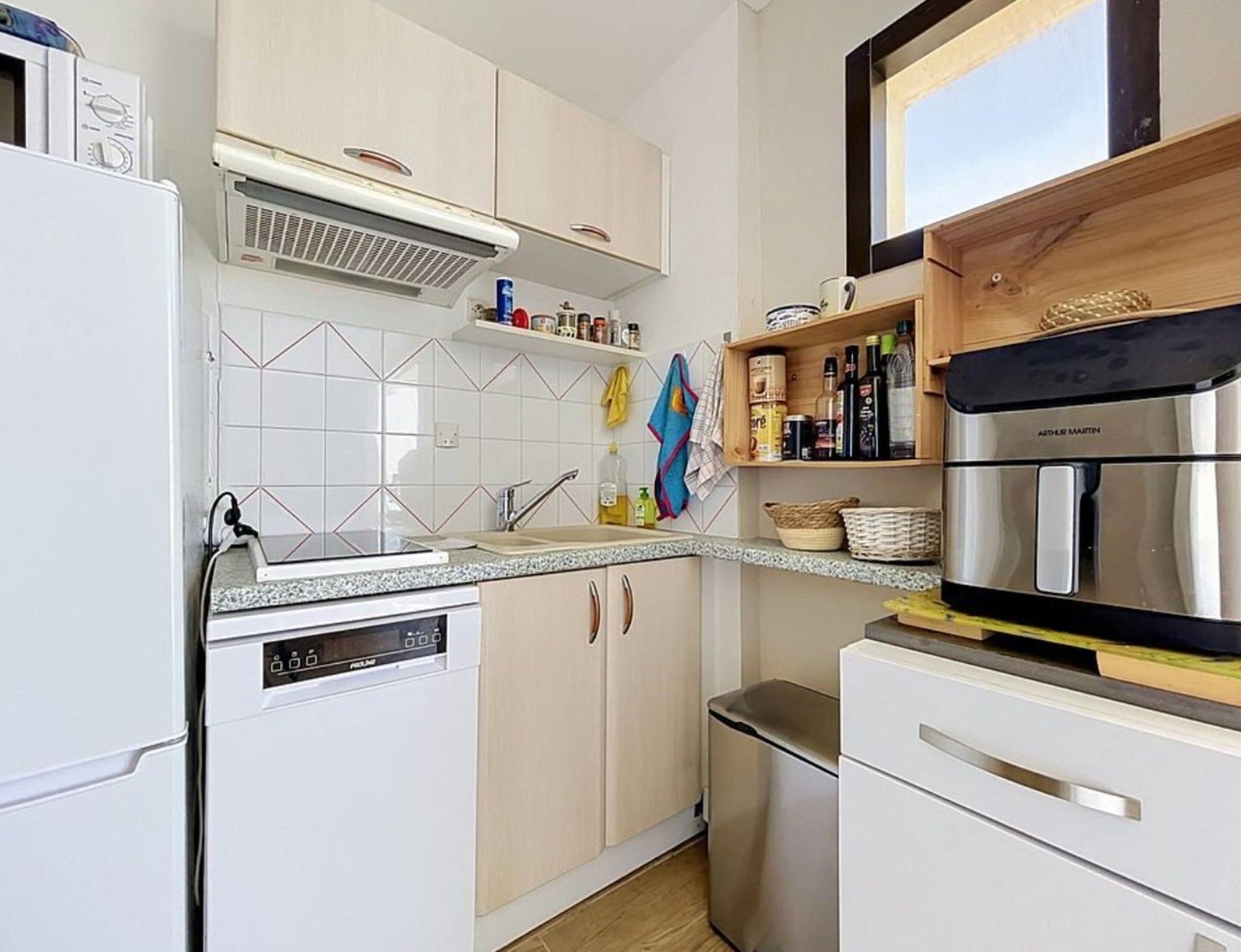 A modern kitchen with white cabinetry, a built-in oven, and a stainless steel range hood.