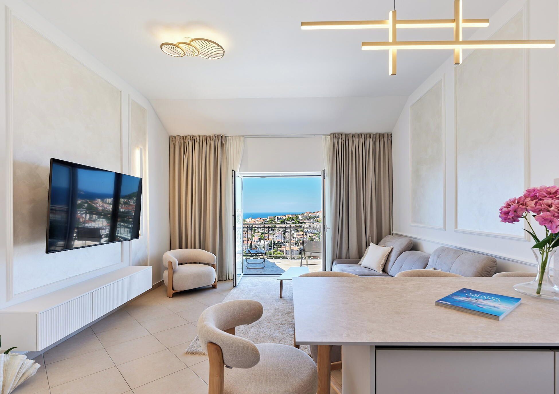 Une chambre d’hôtel moderne dotée d’une grande télévision, d’un canapé, d’un coin repas et offrant une vue sur la ville.