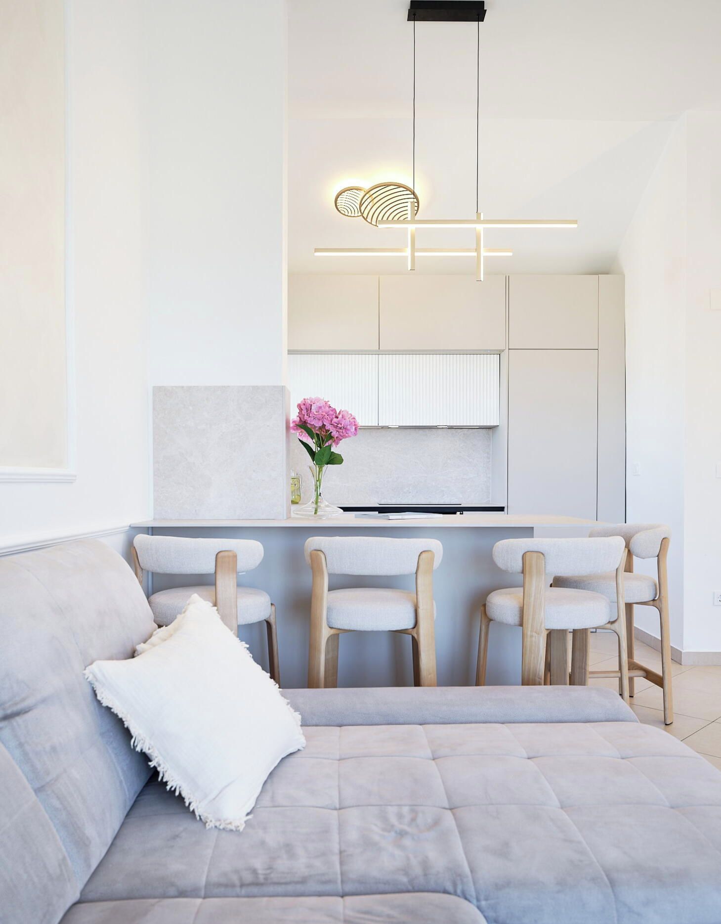 A modern kitchen with white cabinetry, a central island with bar stools, and a pendant light fixture.