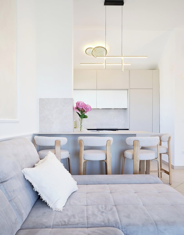 A modern kitchen with white cabinetry, a central island with bar stools, and a pendant light fixture. - Hedera Estate, Hedera A18 (Dubrovnik)