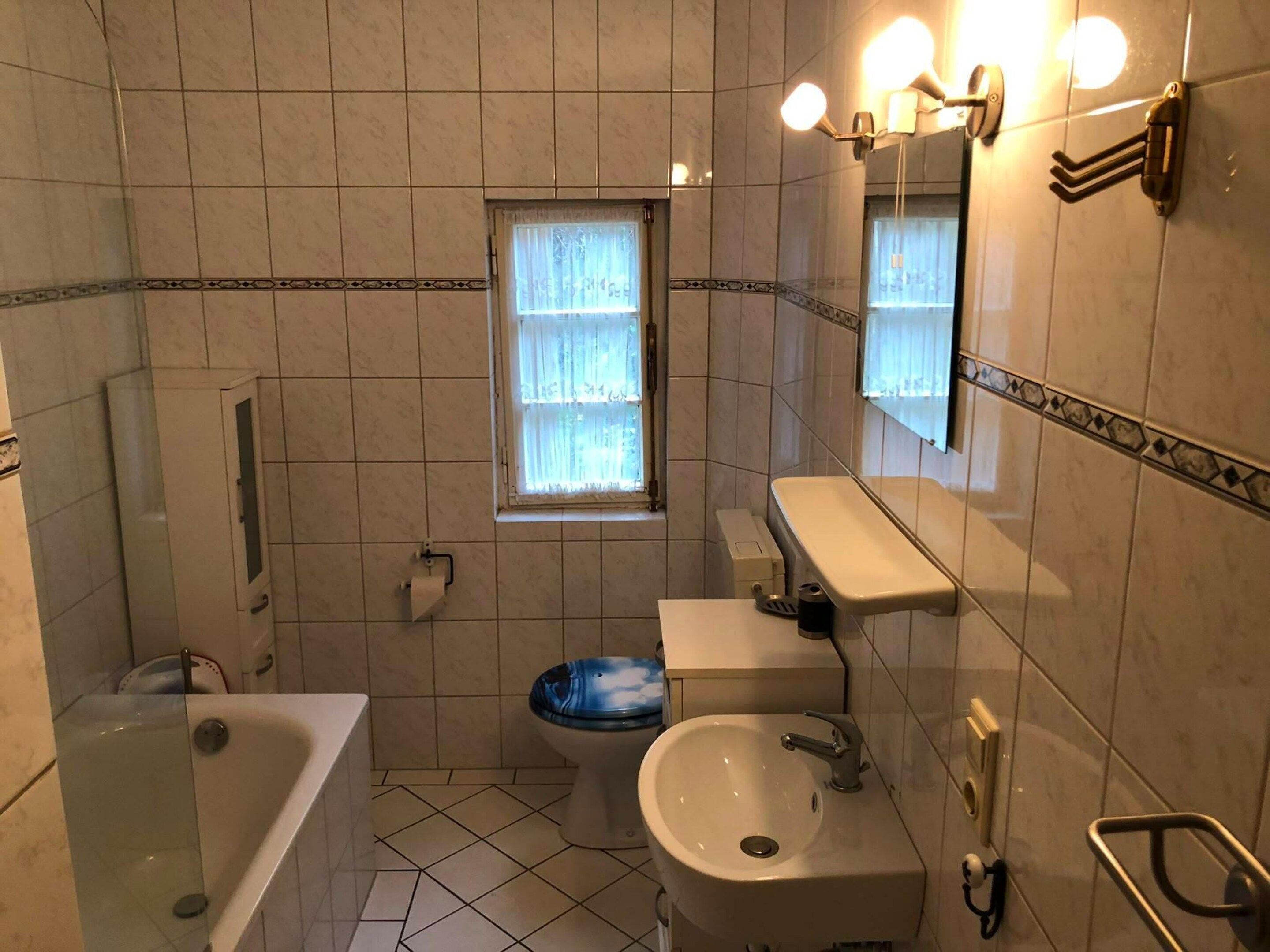 Une salle de bain avec une baignoire, un lavabo, des toilettes, une fenêtre et un miroir.