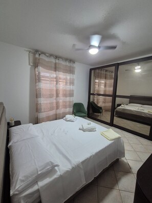 Ein Hotelzimmer mit einem Bett, einem Sessel, einem kleinen Tisch mit Globus und einem fenster mit Vorhängen.