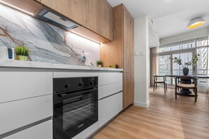 Eine moderne Küche mit Bosch-Ofen, Marmorarbeitsplatte, Holzschränken und Blick auf die Stadt durch große Fenster.