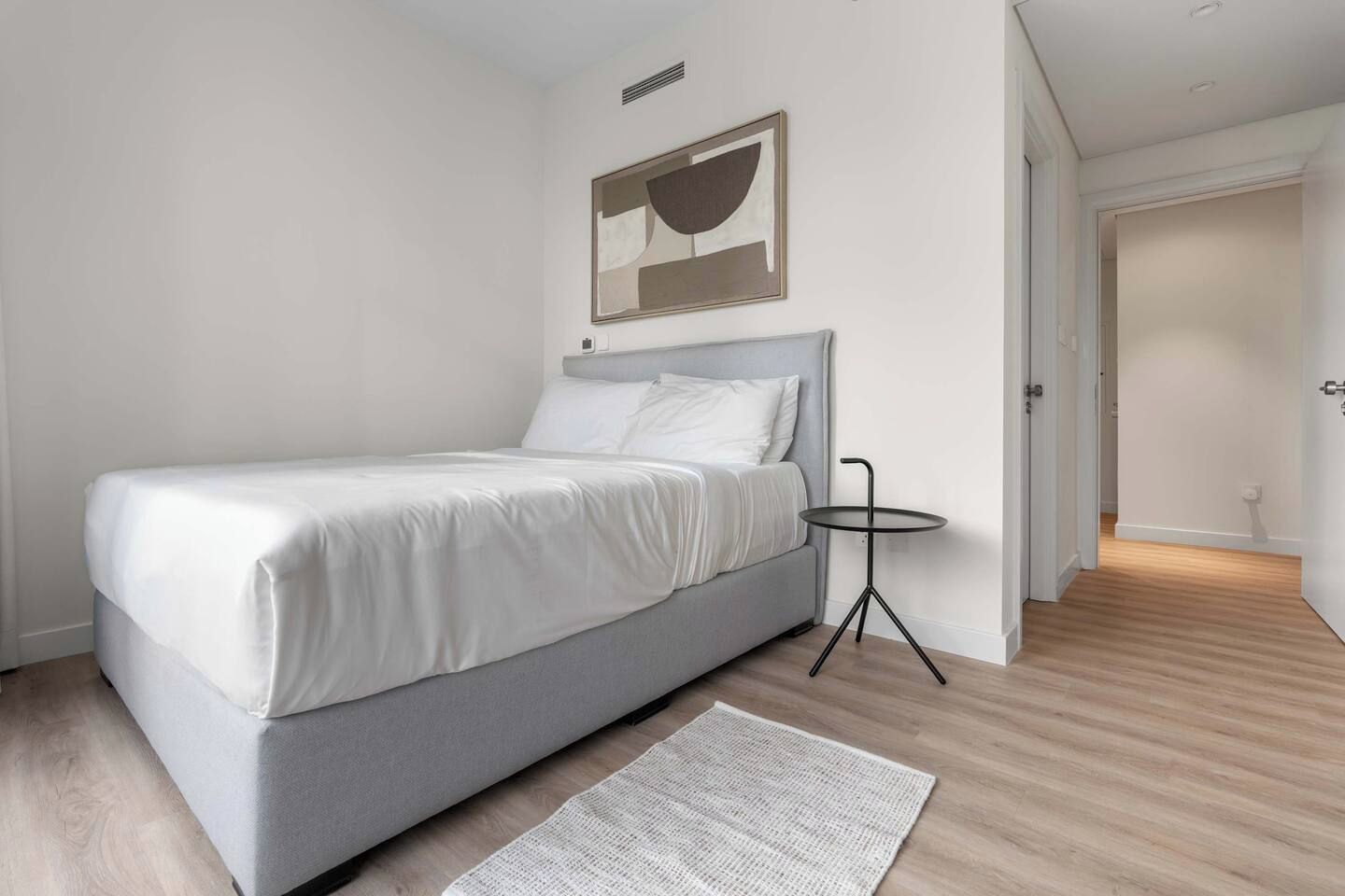 Ein modernes Schlafzimmer mit einem Bett, einem kleinen runden Tisch und einem helffenaren Teppich.