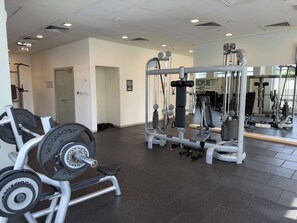 Ein Fitnessraum mit Gewichthebergeräten, einer Bank und einer Spiegelwand.