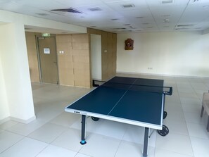 Ein Tischtennis-Tisch in einem Raum mit Fliesenboden, einer Tür und einem an der Wand befestigten Schild.