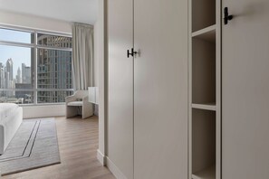 A modern hotel room with a large window, a bed, a chair, and a wardrobe. - Downtown Dubai 2BR near Burj Khalifa & Dubai Mall (Downtown Dubai)