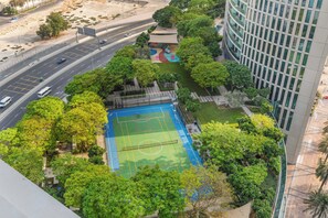An aerial view of a residential area with a sports court surrounded by lush greenery and adjacent to a road. - Downtown Dubai 2BR near Burj Khalifa & Dubai Mall (Downtown Dubai)