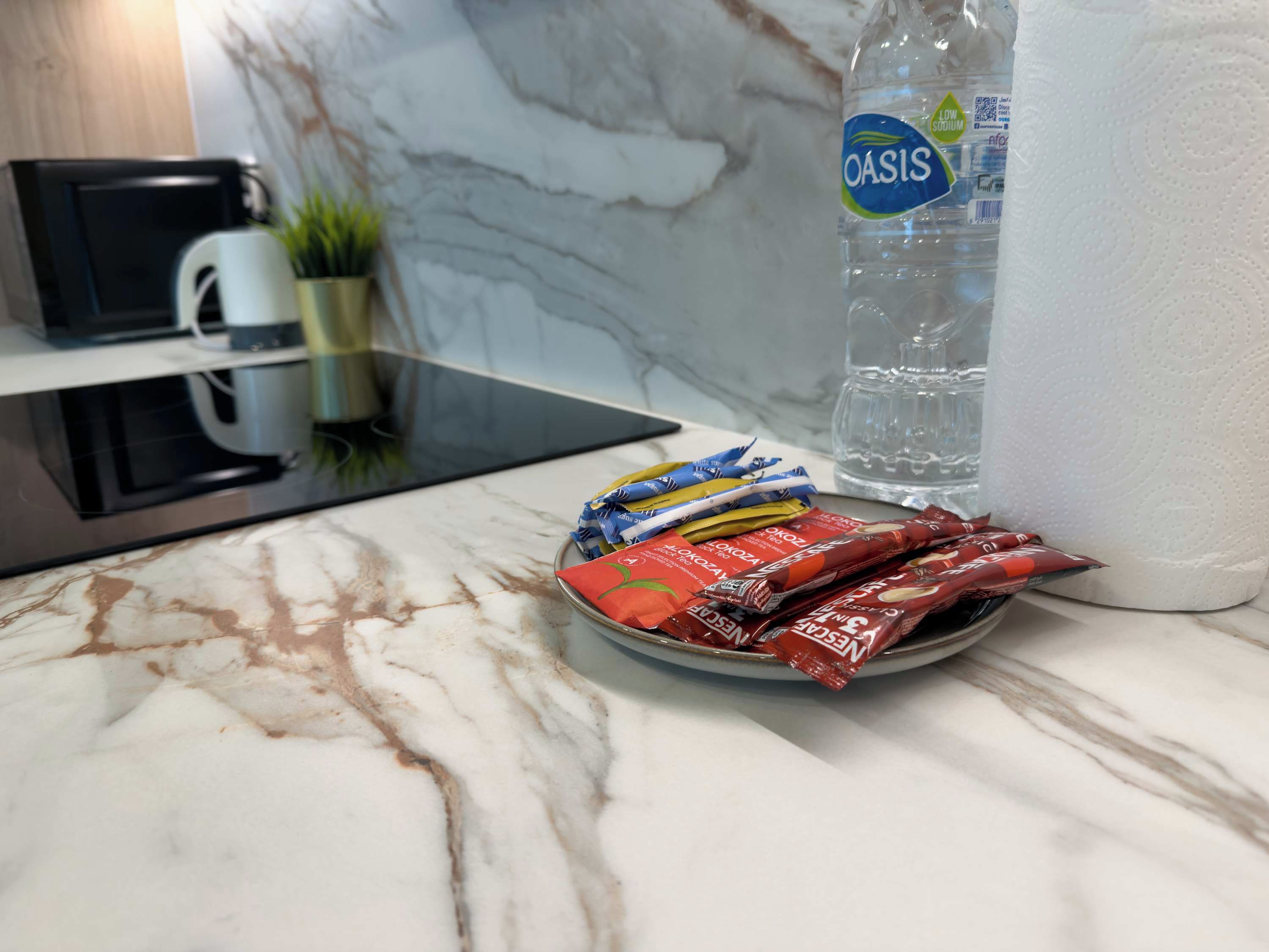 A kitchen counter with a plate of snacks, a bottle of water, and a coffee maker.
