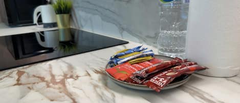 A kitchen counter with a plate of snacks, a bottle of water, and a coffee maker.