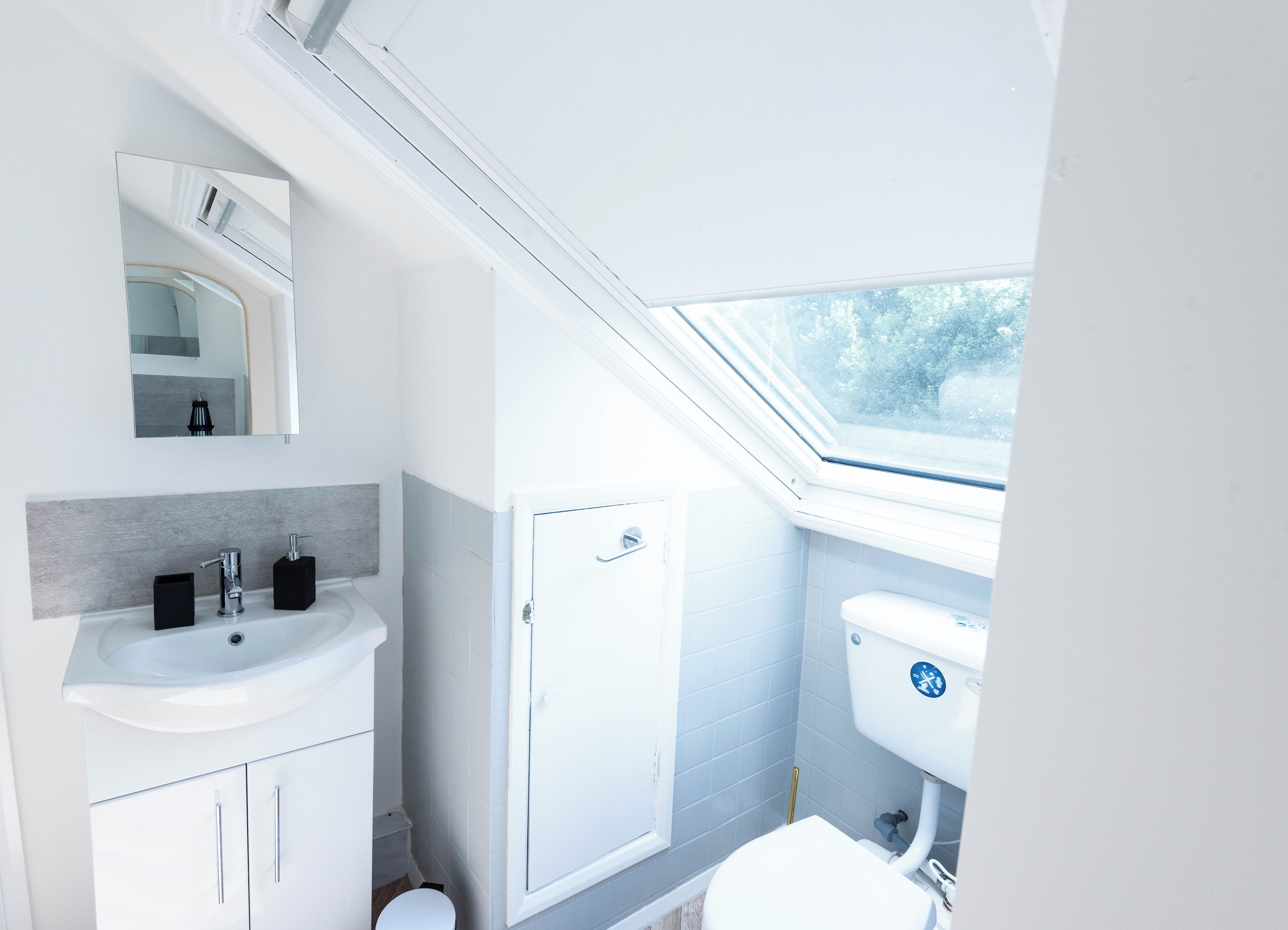 A modern bathroom with a skylight, white fixtures, and a visible toilet.